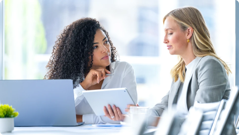 Two women discussing work with tablet